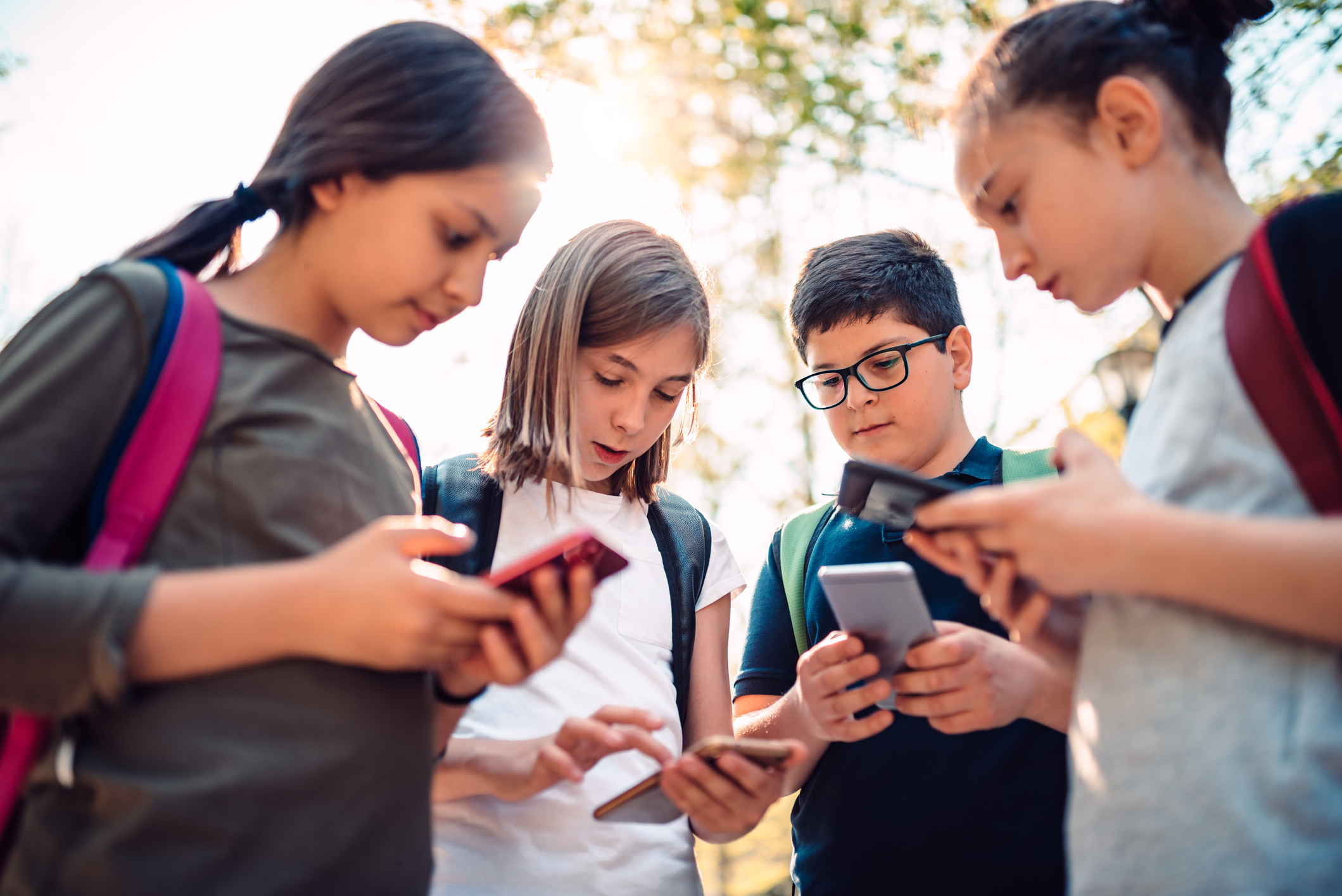 the photo shows a group of young kids in a circle playing on their smart phones