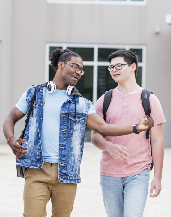 The photo shows a multi-ethnic group of four teenage boys conversing as they walk outside their school building. They are a diverse group, 15 to 17 years old, including two African-British, a mixed race Caucasian/Asian and a redhead.