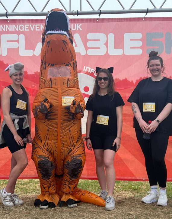 A picture of the With Youth team ready to start the obstacle course. One member of the team is dressed as a dinosaur